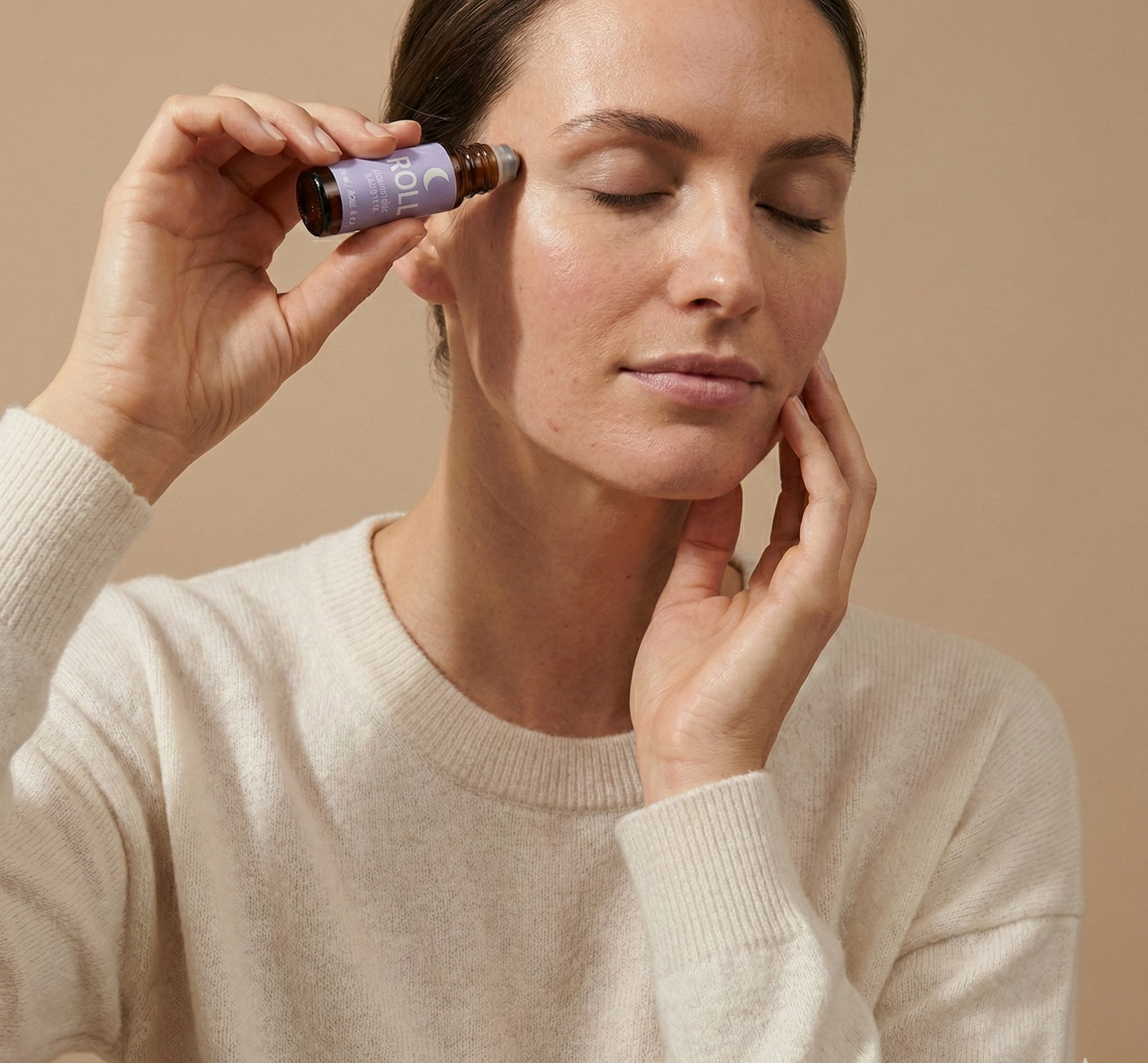 Vrouw brengt ROLL aromatherapie roller aan op haar slaap als natuurlijke routine voor sneller inslapen en rust voor het slapengaan
